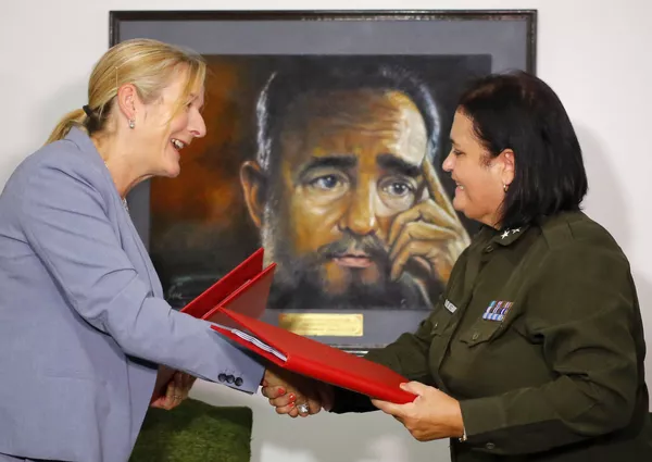 Marie Claude Arsenault, de la policía de Canadá, y Idais Borges Barrios, de la Policía Nacional Revolucionaria de Cuba, estrechan manos con un retrato de Fidel Castro de fondo en La Habana, el 15 de agosto de 2018. Marie Claude Arsenault, de la policía de Canadá, y Idais Borges Barrios, de la Policía Nacional Revolucionaria de Cuba, estrechan manos con un retrato de Fidel Castro de fondo en La Habana, el 15 de agosto de 2018. - Sputnik Mundo