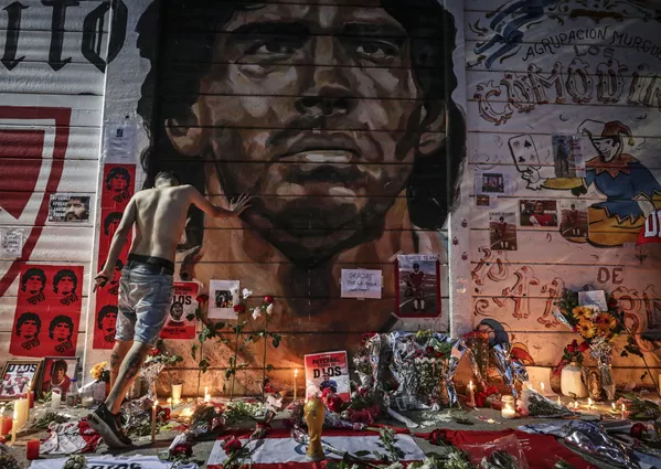Un altar improvisado en homenaje a Maradona montado el día de su muerte en 2020 por los aficionados del equipo de fútbol Argentinos Juniors, en el cual actuó la leyenda del fútbol argentino. Un altar improvisado en homenaje a Maradona montado el día de su muerte en 2020 por los aficionados del equipo de fútbol Argentinos Juniors, en el cual actuó la leyenda del fútbol argentino. - Sputnik Mundo