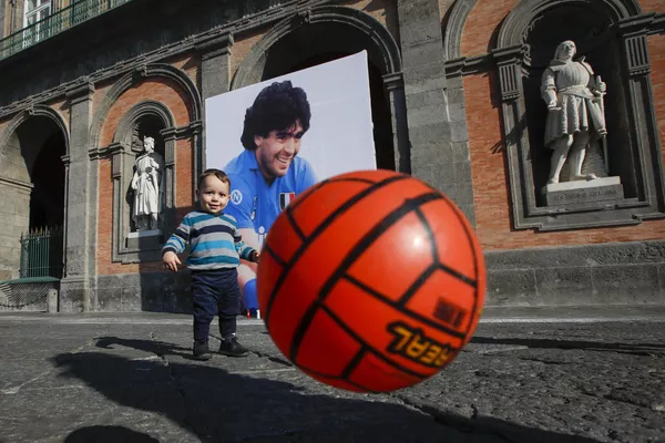 Andrea Cangiano, de 16 meses, juega con un balón frente a una imagen de Maradona delante del Palacio Real de Nápoles (Italia) el 27 de noviembre de 2020. El crac argentino jugó por el Nápoles entre los años de 1984 y 1992. Andrea Cangiano, de 16 meses, juega con un balón frente a una imagen de Maradona delante del Palacio Real de Nápoles (Italia) el 27 de noviembre de 2020. El crac argentino jugó por el Nápoles entre los años de 1984 y 1992. - Sputnik Mundo