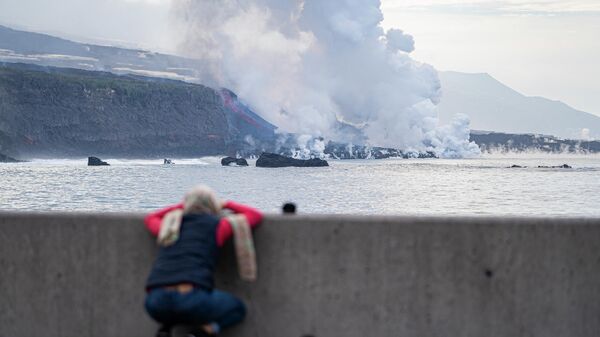 Una persona observa la colada de lava a su llegada al mar, - Sputnik Mundo