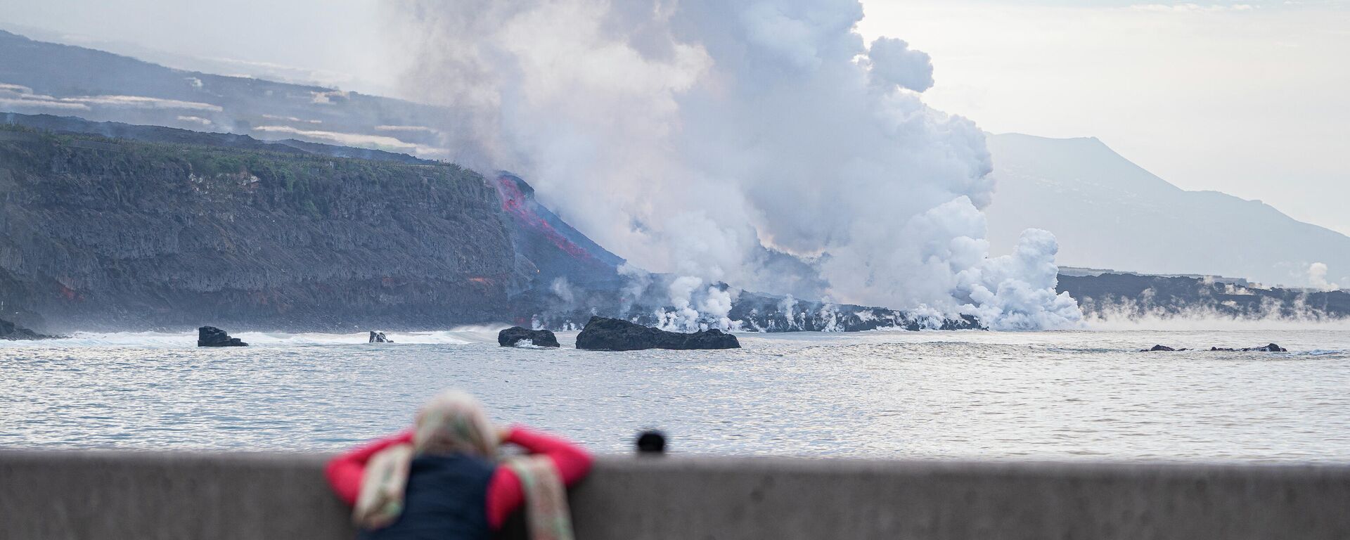 Una persona observa la colada de lava a su llegada al mar, - Sputnik Mundo, 1920, 25.11.2021