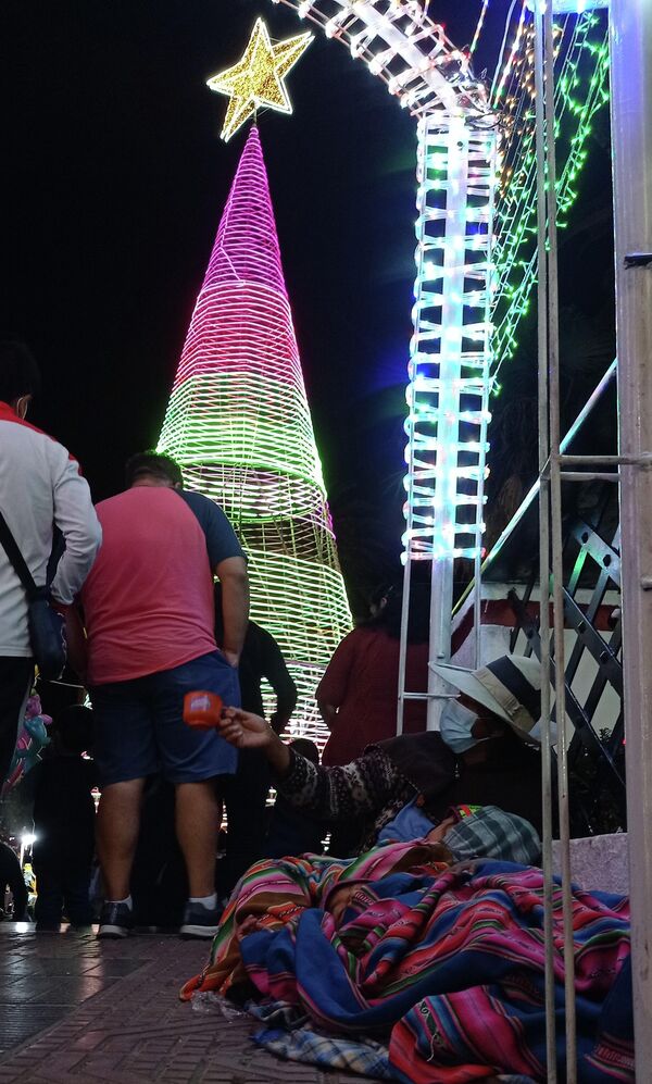 En tiempos de fiestas, cientos de familias de áreas rurales se trasladan a las principales ciudades, donde mendigan en medio del paisaje estrambótico. Algunos trabajadores ya cobraron su aguinaldo, lo cual les permite dejar caer monedas en las precarias tacitas de señoras y niños que pasan necesidades. - Sputnik Mundo