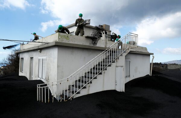 Después de una semana de inactividad del volcán, las autoridades permitieron a los residentes volver a sus casas a pocos días de celebrarse la Navidad. En la foto: militares retiran las cenizas volcánicas de una casa en la isla de La Palma. - Sputnik Mundo