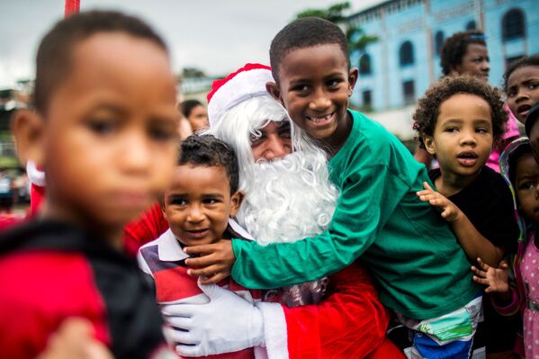 Entre las tradiciones más populares de la cena de Nochebuena figura la de dejar un asiento libre para un posible huésped.En la foto: un hombre disfrazado de Papá Noel reparte comida en una favela de Río de Janeiro, en Brasil. - Sputnik Mundo