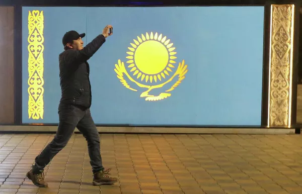 Un hombre pasa frente a la bandera de Kazajistán durante las protestas en Almaty