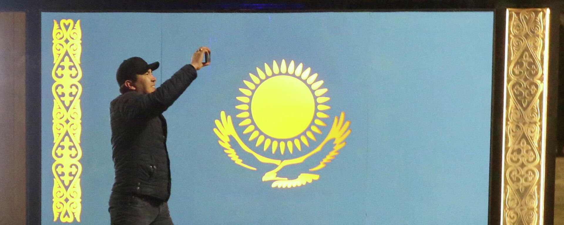 Un hombre pasa frente a la bandera de Kazajistán durante las protestas en Almaty - Sputnik Mundo, 1920, 05.01.2022