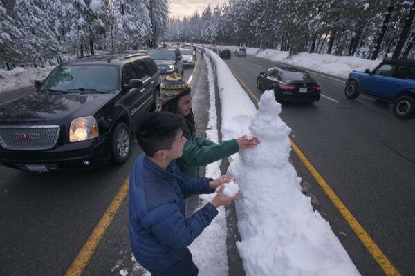 Unos jóvenes en un atasco hacen un muñeco de nieve en Pollock Pines, California, EEUU, el 28 de diciembre de 2021. - Sputnik Mundo