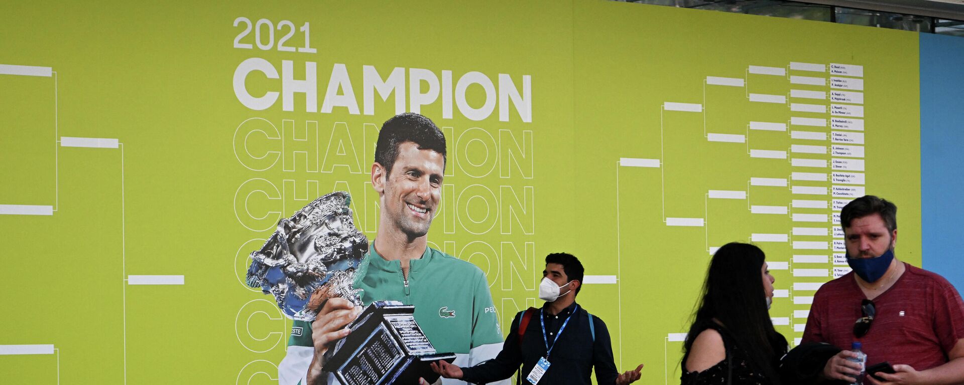 La gente frente a una foto de Novak Djokovic en el primer día del Open de Australia en Melbourne Park, el 17 de enero de 2022  - Sputnik Mundo, 1920, 18.01.2022