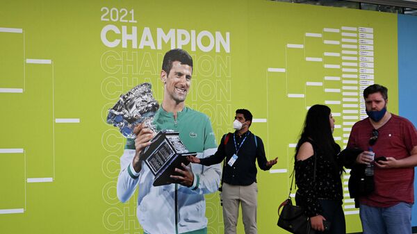 La gente frente a una foto de Novak Djokovic en el primer día del Open de Australia en Melbourne Park, el 17 de enero de 2022  - Sputnik Mundo