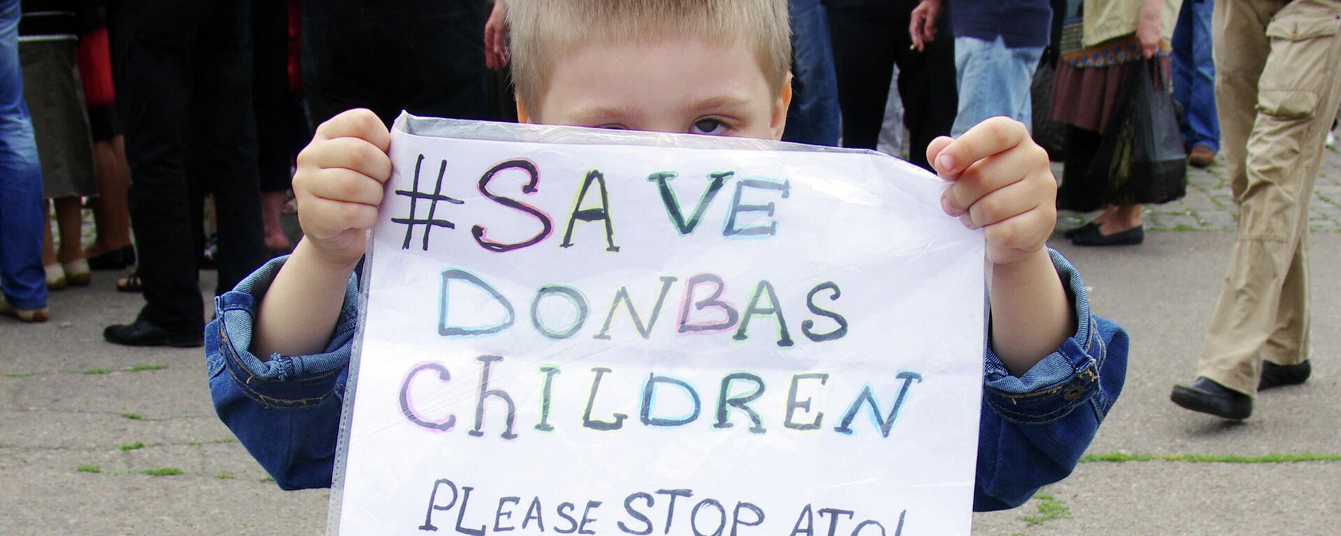 Un niño en Donbás muestra el póster Save Donbas children. Please stop ATO! Un niño en Donbás muestra el póster Save Donbas children. Please stop ATO! - Sputnik Mundo, 1920, 21.01.2022