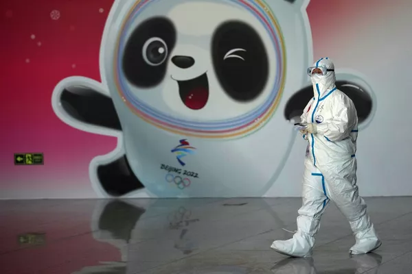 Un funcionario médico con traje de protección en el aeropuerto de Shawdue, en Pekín. En el fondo hay una imagen de la mascota oficial de los Juegos Olímpicos de Invierno de 2022, el panda Bing Dong. Un funcionario médico con traje de protección en el aeropuerto de Shawdue, en Pekín. En el fondo hay una imagen de la mascota oficial de los Juegos Olímpicos de Invierno de 2022, el panda Bing Dong. - Sputnik Mundo