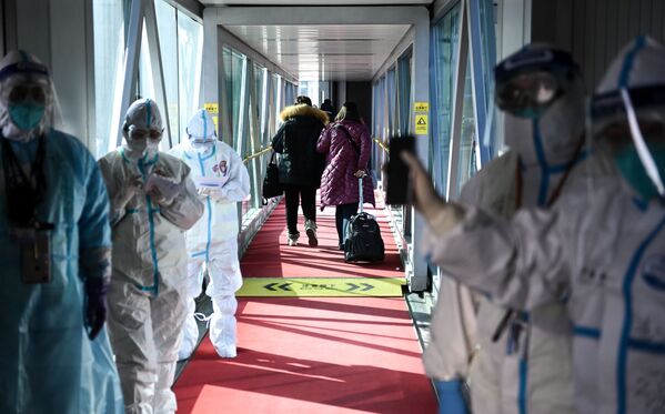 Personal médico con trajes de protección en una rampa telescópica del aeropuerto de Pekín (China). Personal médico con trajes de protección en una rampa telescópica del aeropuerto de Pekín (China). - Sputnik Mundo