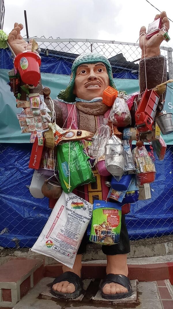 Ekeko es el dios de la suerte y de la abundancia para el pueblo Aymara. Se lo representa cargado de productos de todo tipo: camiones, casas, sacos de harina, azúcar, lentejas, radios, celulares. Lo que sea, pero en miniatura. Generalmente lo pintan de ojos celestes, con un infaltable cigarro entre los labios. - Sputnik Mundo