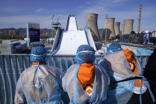 Miembros del personal de apoyo observan la competición de saltos de big air femenino en el Big Air Shogen del Parque de Nieve de Shougang, en Pekín. - Sputnik Mundo