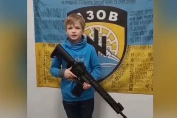 Un niño ucraniano con un fusil posa frente a un símbolo nazi, captura de pantalla Un niño ucraniano con un fusil posa frente a un símbolo nazi, captura de pantalla - Sputnik Mundo
