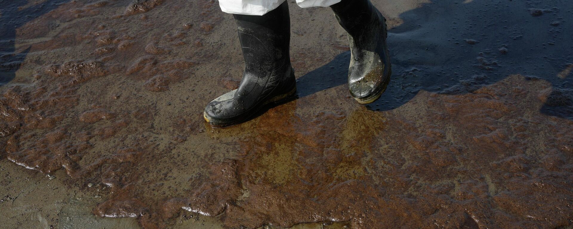 Un trabajador de limpieza camina por la playa de Cavero, contaminada por petróleo, en Ventanilla, Callao, Perú - Sputnik Mundo, 1920, 15.09.2022