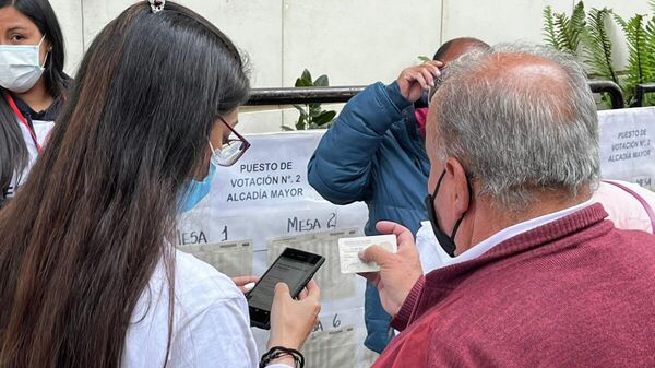 Un bogotano le está pidiendo ayuda a una persona de la Registraduría para poder ubicar su mesa de votación. Sólo con el número de cédula de ciudadanía, el personal de Infovotantes puede guiar a los electores.  - Sputnik Mundo