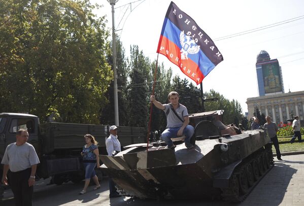 En marzo de 2015, el Parlamento ucraniano reconoció a la República Popular de Donetsk (RPD) y la República Popular de Lugansk (RPL) como &quot;territorios temporalmente ocupados&quot;. De hecho, la ley sobre el estatus especial de Donbás fue bloqueada.En la foto: Un hombre con la bandera de la República Popular de Donetsk sobre un vehículo militar ucraniano blindado en la Plaza Lenin de Donetsk. - Sputnik Mundo