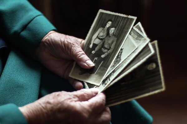 Maria Popova, veterana de la Segunda Guerra Mundial, operadora de radio y participante en la toma de Berlín, ve viejas fotos en su casa de Donetsk. - Sputnik Mundo