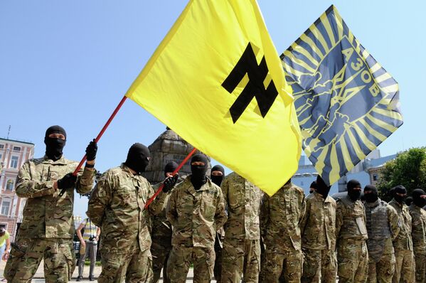 Azov se destacó, entre otros batallones de voluntarios neonazis, por su fuerte entrenamiento ideológico. Las principales posiciones en el batallón fueron ocupadas por los neonazis, antisemitas y racistas. El simbolismo de la unidad hace referencia a los emblemas de las formaciones militares del Tercer Reich. Así, su bandera representa el Wolfsangel (trampa de lobos), el símbolo heráldico alemán, utilizado en sus orígenes por el Partido Nazi y posteriormente por algunas divisiones de las Waffen-SS y la Wehrmacht.En la foto: los combatientes del batallón Azov toman juramento en Kiev, en 2014. - Sputnik Mundo