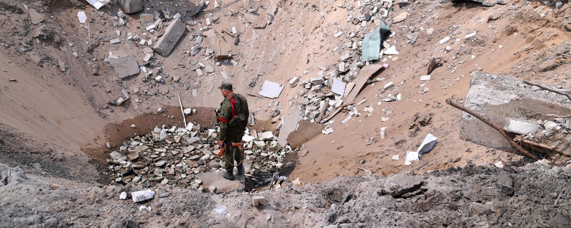 Un militar de la República Popular de Lugansk se para sobre un socavón que resultó de un ataque aéreo de las Fuerzas Armadas de Ucrania en el pueblo de Yatskovka, en el territorio del distrito Liman de la República Popular de Donetsk. - Sputnik Mundo, 1920, 30.09.2022