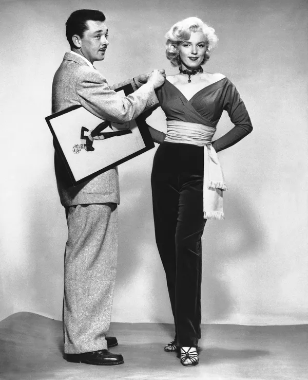 En diciembre de 1950, Marilyn firmó un contrato de siete años con 20th Century Fox. Finalmente comenzó a obtener papeles protagónicos, pero en su mayoría eran papeles de rubias tontas. Sin embargo, su carrera fue cobrando impulso, y en 1953, tras el estreno de las películas Niagara y Gentlemen Prefer Blondes, se convirtió en uno de los principales símbolos sexuales y la actriz más rentable de Hollywood. Ese mismo año, su fotografía salió en la portada de la primera edición de la revista para adultos Playboy. En la foto: Marilyn Monroe probándose un vestido en el set de Gentlemen Prefer Blondes, 1953. En diciembre de 1950, Marilyn firmó un contrato de siete años con 20th Century Fox. Finalmente comenzó a obtener papeles protagónicos, pero en su mayoría eran papeles de rubias tontas. Sin embargo, su carrera fue cobrando impulso, y en 1953, tras el estreno de las películas Niagara y Gentlemen Prefer Blondes, se convirtió en uno de los principales símbolos sexuales y la actriz más rentable de Hollywood. Ese mismo año, su fotografía salió en la portada de la primera edición de la revista para adultos Playboy. En la foto: Marilyn Monroe probándose un vestido en el set de Gentlemen Prefer Blondes, 1953. - Sputnik Mundo