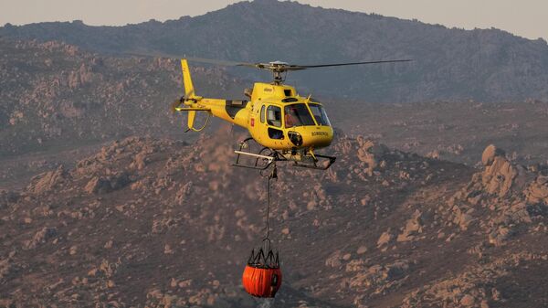 Un helicópterpo con agua durante incendios forestales en España - Sputnik Mundo