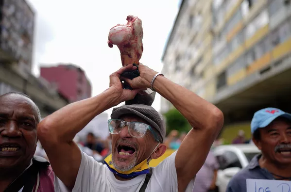 Un manifestante sujeta un hueso para simbolizar el hambre en una protesta llevada a cabo por empleados públicos activos y jubilados, incluidos los maestros. Exigen que les aumenten los salarios y que se les pague el resto de su bonificación de vacaciones que aseguran que se les pagó solo parcialmente. La macha se celebró el 2 de agosto y llegó hasta el Ministerio de Trabajo en Caracas. - Sputnik Mundo