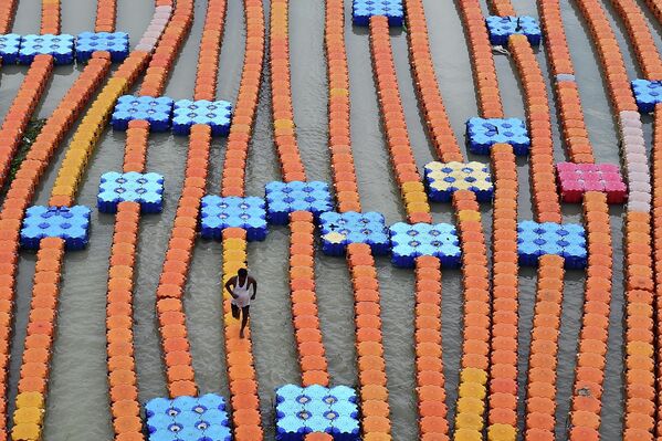 Un barquero camina sobre un muelle flotante hecho de cubos de plástico a lo largo de las orillas inundadas del río Ganges tras una subida del nivel del agua debido a las fuertes lluvias en Allahabad, el 30 de julio de 2022. - Sputnik Mundo