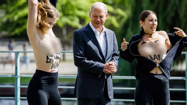 El par de activistas se desnudaron de cintura para arriba donde se habían escrito embargo al gas ruso cerca del canciller alemán, Olaf Scholz - Sputnik Mundo