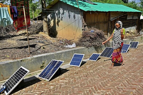 Una mujer pasa frente a unos paneles solares en un campo de refugiados rohinyá en Ukhia, Bangladés. - Sputnik Mundo