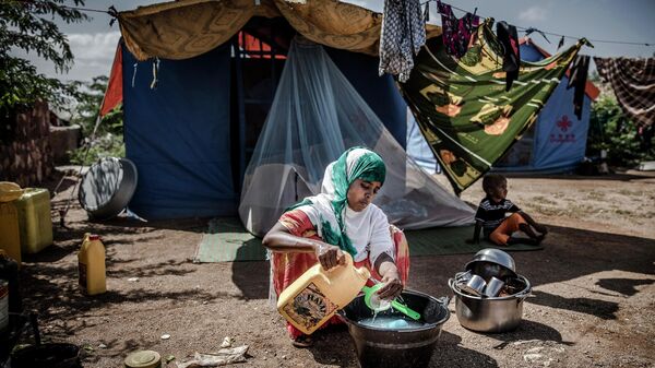 Una mujer desplazada lava algunos platos y utensilios frente a su tienda de campaña en un campo de desplazados en Beledweyne, Somalia  - Sputnik Mundo