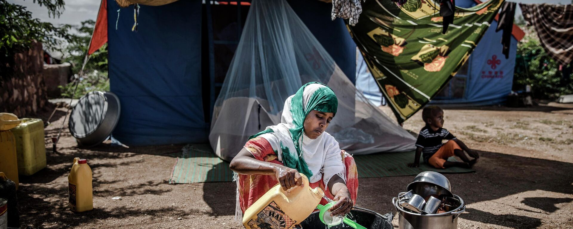 Una mujer desplazada lava algunos platos y utensilios frente a su tienda de campaña en un campo de desplazados en Beledweyne, Somalia  - Sputnik Mundo, 1920, 13.09.2022