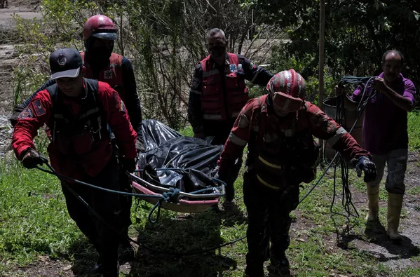 Los socorristas transportan el cuerpo de un fallecido recuperado de debajo de un desprendimiento de tierra a orillas del río Tuy. Los socorristas transportan el cuerpo de un fallecido recuperado de debajo de un desprendimiento de tierra a orillas del río Tuy. - Sputnik Mundo