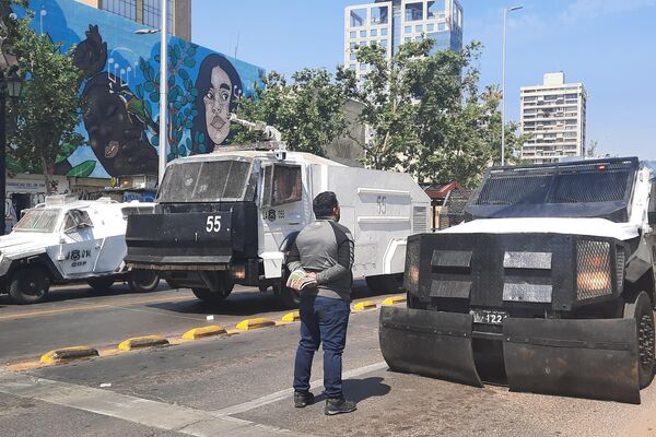 Un manifestante frente a un carro lanzagases de Carabineros - Sputnik Mundo