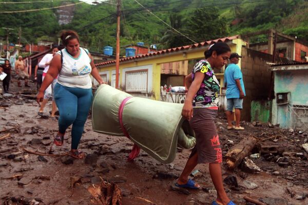 Las fuertes lluvias en Venezuela han vuelto a provocar inundaciones y deslaves. Al menos seis personas han sido encontradas muertas bajo los escombros en la ciudad norteña de Puerto La Cruz. En la foto, los habitantes de la localidad sacan sus pertenencias de las casas destruidas por el deslizamiento de tierra. - Sputnik Mundo