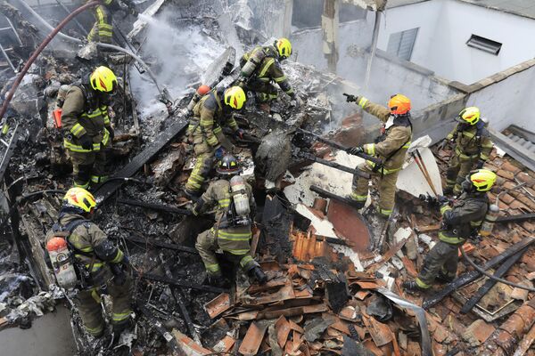 Los bomberos en el lugar del accidente de un avión de pasajeros en Medellín, Colombia. La aeronave al intentar aterrizar se estrelló en una zona residencial de la ciudad poco después de despegar del aeropuerto Olaya Herrera. Tras el accidente aéreo seis pasajeros y dos miembros de la tripulación que iban a bordo perdieron la vida. - Sputnik Mundo