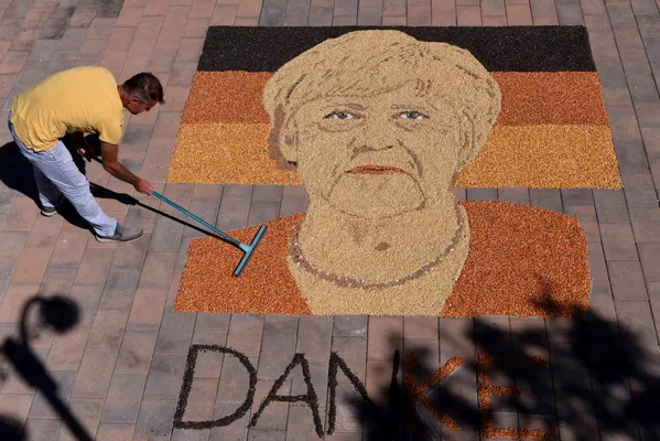 En vísperas de la dimisión de la canciller alemana Angela Merkel el artista kosovar Alkent Pozhegu completa su retrato en la plaza de la ciudad de Gjakova, creándolo con semillas y granos. En vísperas de la dimisión de la canciller alemana Angela Merkel el artista kosovar Alkent Pozhegu completa su retrato en la plaza de la ciudad de Gjakova, creándolo con semillas y granos. - Sputnik Mundo