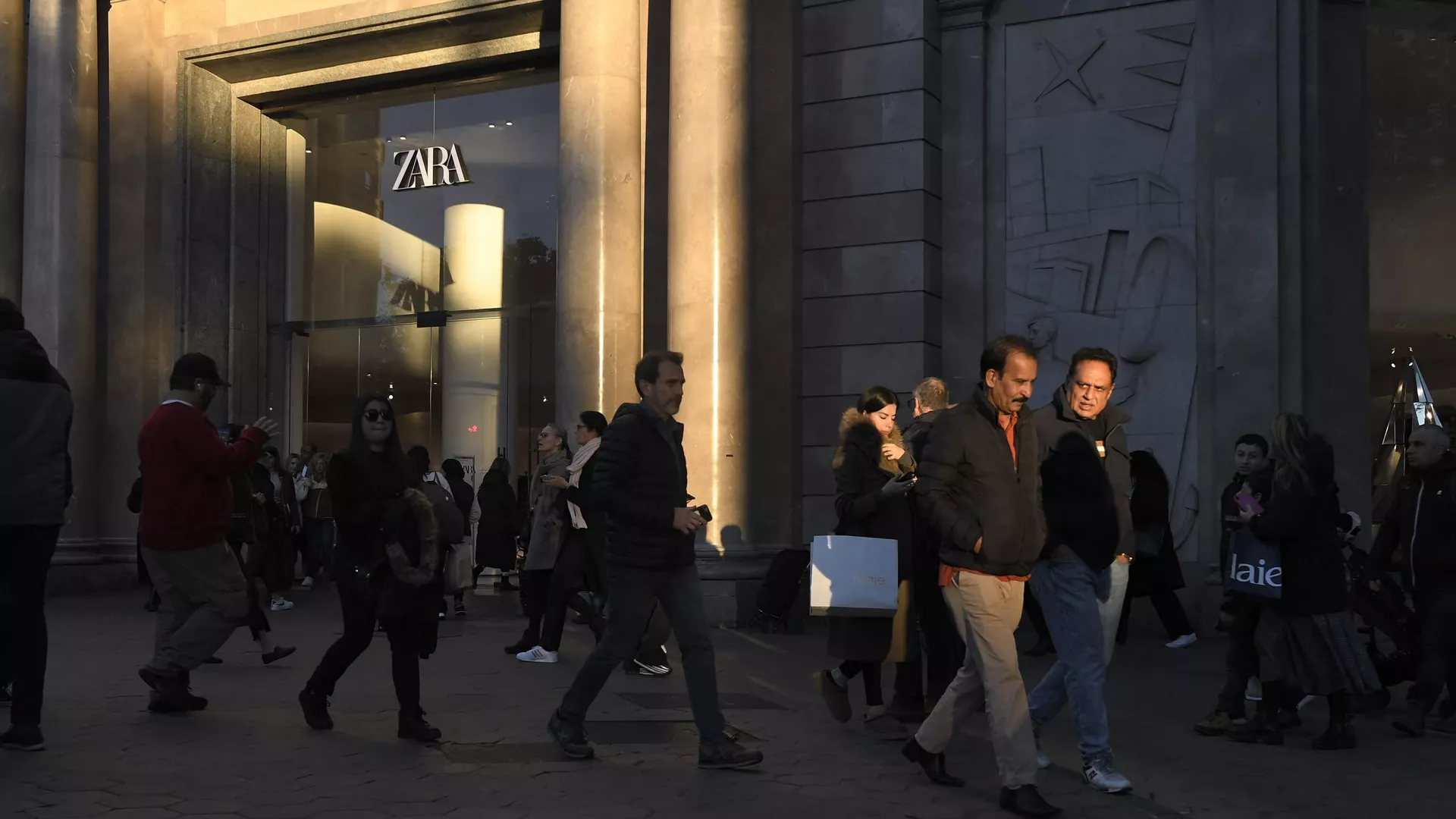 Personas pasan por una calle comercial de Barcelona, 10 de diciembre 