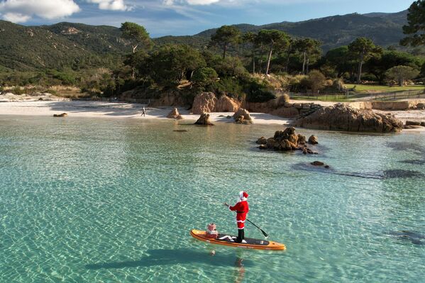 Una mujer vestida de Papá Noel en una tabla de remo frente a la costa de Córcega, Italia. - Sputnik Mundo