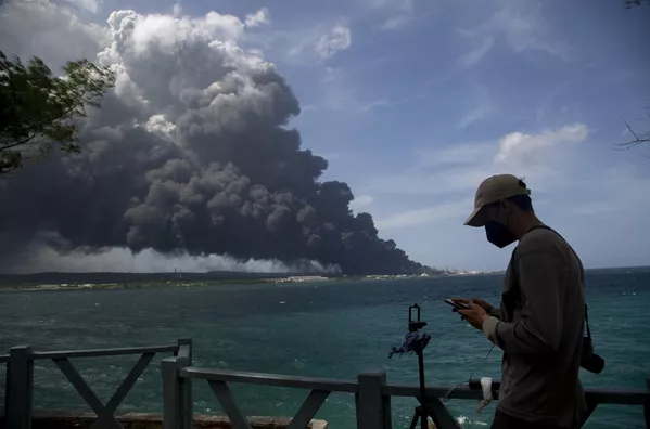 Un hombre escribe en su celular durante el accidente petrolero de la base de reserva de supertanques en Matanzas, Cuba, durante la operación de bomberos para amansar el incendio. Las autoridades cubanas advirtieron el 8 de agosto que un relámpago golpeó uno de los tanques de reserva de crudo, lo que generó una llama que se esparció hasta producir cuatro explosiones. Un hombre escribe en su celular durante el accidente petrolero de la base de reserva de supertanques en Matanzas, Cuba, durante la operación de bomberos para amansar el incendio. Las autoridades cubanas advirtieron el 8 de agosto que un relámpago golpeó uno de los tanques de reserva de crudo, lo que generó una llama que se esparció hasta producir cuatro explosiones. - Sputnik Mundo