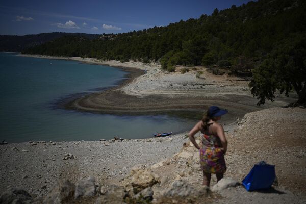 Una bañista de pie el 9 de agosto frente a la retrocedida línea de playa de las Gargantas del Verdon, en el sur de Francia, durante la cuarta ola de calor registrada en 2022 en el país europeo. Las autoridades advirtieron que Francia enfrentaba su peor sequía de la que se tenga registro.  - Sputnik Mundo