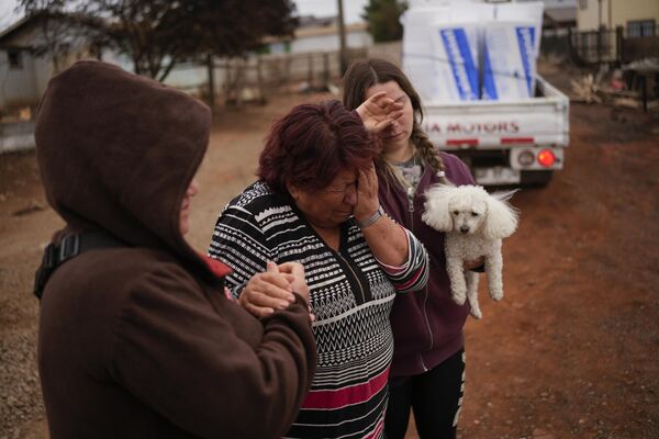 Entre los fallecidos hay dos hombres y una mujer que participaron en la extinción de los incendios, así como varias personas que sufrieron accidentes mortales cuando intentaban huir de las zonas peligrosas.En la foto: vecinos consuelan a una mujer que perdió su casa durante el incendio forestal en Tome. Entre los fallecidos hay dos hombres y una mujer que participaron en la extinción de los incendios, así como varias personas que sufrieron accidentes mortales cuando intentaban huir de las zonas peligrosas.En la foto: vecinos consuelan a una mujer que perdió su casa durante el incendio forestal en Tome. - Sputnik Mundo