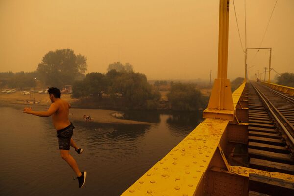 La lucha contra los incendios se ve dificultada por el denso humo que reduce enormemente la visibilidad.En la foto: un residente salta al agua en Renaico, donde los incendios forestales arrasan los alrededores. La lucha contra los incendios se ve dificultada por el denso humo que reduce enormemente la visibilidad.En la foto: un residente salta al agua en Renaico, donde los incendios forestales arrasan los alrededores. - Sputnik Mundo