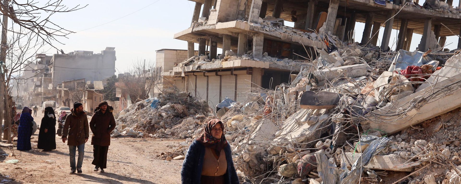 Residentes caminan junto a edificios destruidos, mientras continúan las operaciones de búsqueda y rescate días después de que un mortífero terremoto  en la ciudad de Jindayris, en la parte de la provincia siria de Alepo, el 10 de febrero de 2023 - Sputnik Mundo, 1920, 13.02.2023