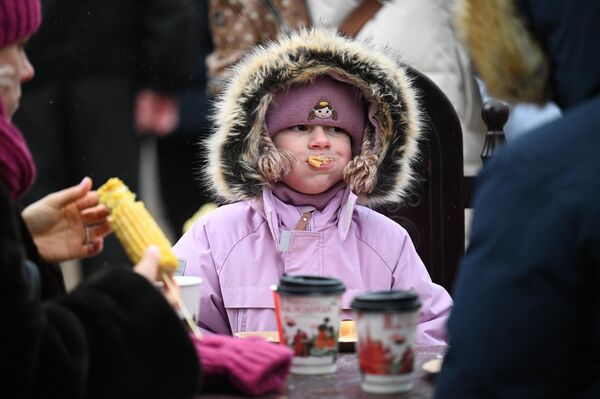 Durante la semana de la Máslenitsa se celebran actuaciones festivas por todo el país y estás van acompañadas de la preparación de platos tradicionales, entre los que destacan los blinis.En la foto: una niña come blinis en la Plaza de la Revolución de Moscú. - Sputnik Mundo