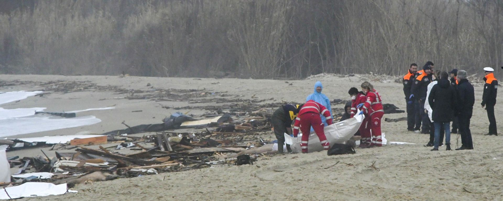 Rescatistas recuperan un cuerpo después de que un bote de migrantes se partiera en medio del mar embravecido, en una playa cerca de Cutro, sur de Italia, domingo 26 de febrero de 2023. - Sputnik Mundo, 1920, 26.02.2023