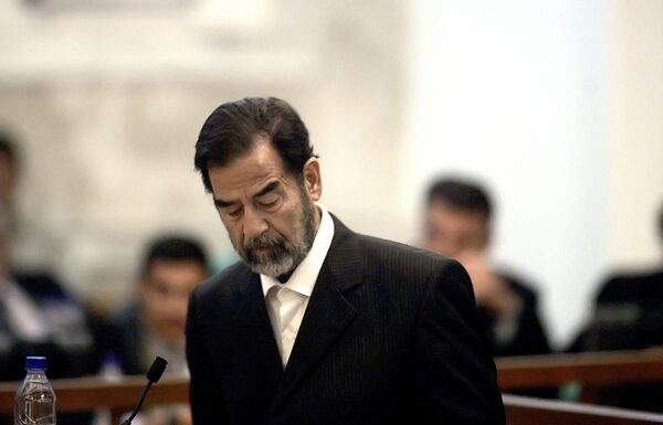 El expresidente iraquí Sadam Huseín declara luego de que el juez principal, Raouf Abdel Rahman, leyera los cargos contra el exgobernante durante un juicio celebrado en la fuertemente fortificada Zona Verde de Bagdad, el 15 de mayo de 2006.Sadam Huseín se negó a declarar cuando se anunciaron los cargos en el juicio tras un aplazamiento de tres semanas. - Sputnik Mundo