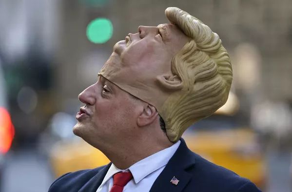 Un hombre llevando una máscara de Donald Trump frente a la Torre Trump en Nueva York, donde se congregó una multitud para esperar la llegada del expresidente estadounidense. Un hombre llevando una máscara de Donald Trump frente a la Torre Trump en Nueva York, donde se congregó una multitud para esperar la llegada del expresidente estadounidense. - Sputnik Mundo