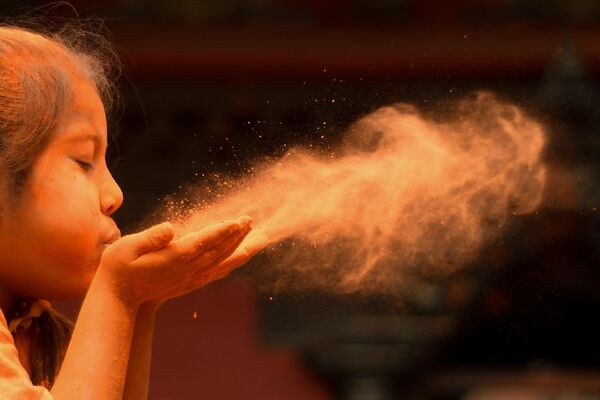Una niña sopla polvos de colores durante las celebraciones del Año Nuevo Bisket Jatra en Katmandú, Nepal. Una niña sopla polvos de colores durante las celebraciones del Año Nuevo Bisket Jatra en Katmandú, Nepal. - Sputnik Mundo
